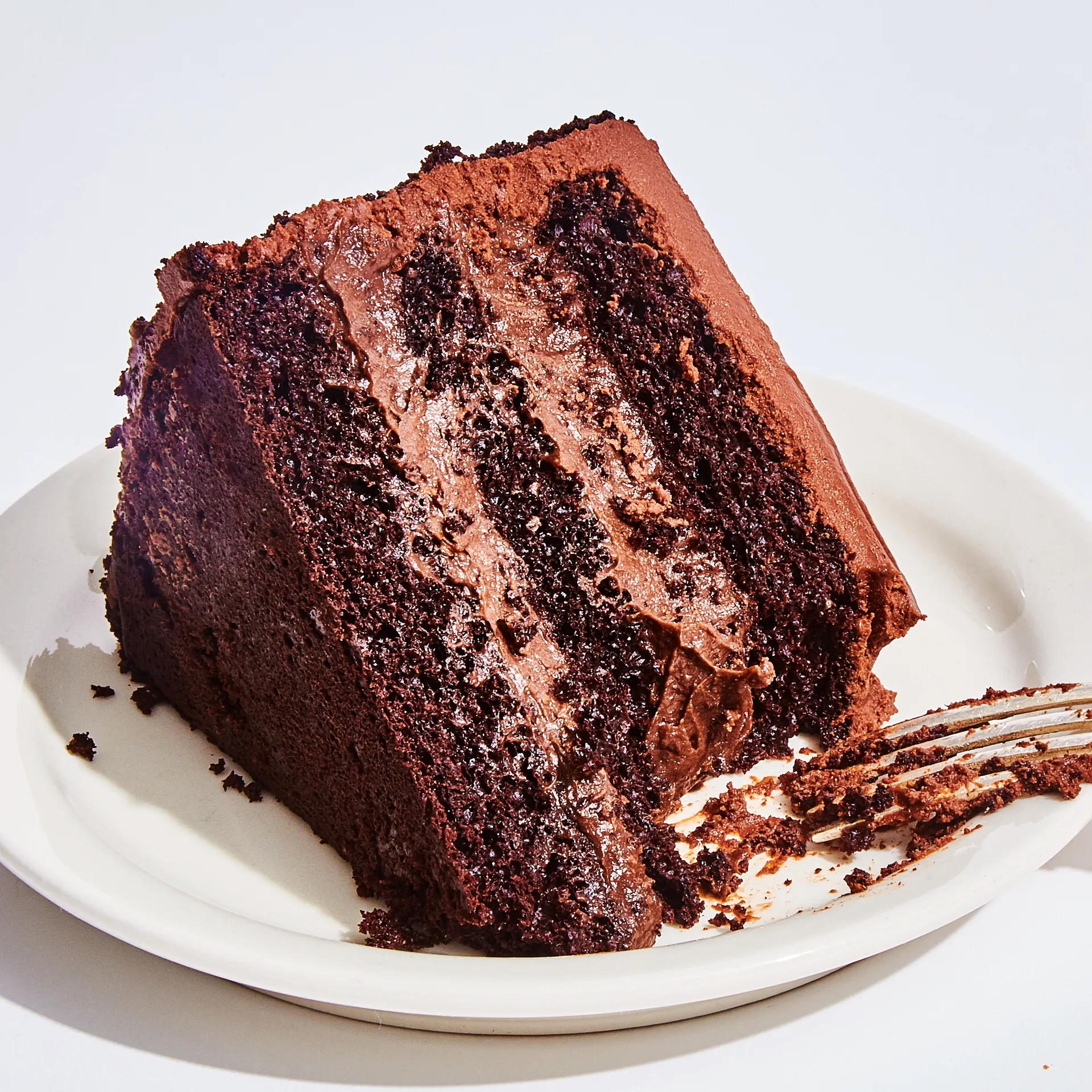 A tall slice of Brooklyn Blackout Cake showing moist chocolate layers, pudding filling, and chocolate crumb coating.