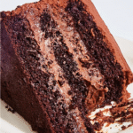 A tall slice of Brooklyn Blackout Cake showing moist chocolate layers, pudding filling, and chocolate crumb coating.