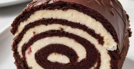 Black Forest cake roll with chocolate sponge, cherry cream cheese filling and glossy chocolate ganache, topped with whole cherries.