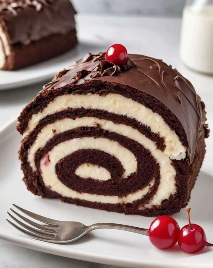 Black Forest cake roll with chocolate sponge, cherry cream cheese filling and glossy chocolate ganache, topped with whole cherries.
