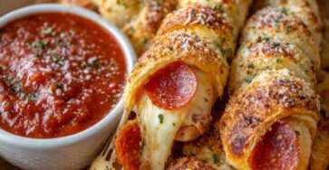Golden baked cheesy pepperoni pizza sticks filled with melted mozzarella, brushed with garlic butter and served with marinara sauce.