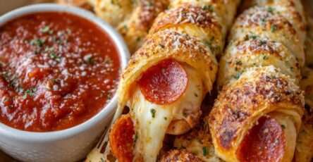 Golden baked cheesy pepperoni pizza sticks filled with melted mozzarella, brushed with garlic butter and served with marinara sauce.