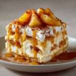 A glass dessert layered with caramelized apples, mascarpone cream and soaked ladyfingers, topped with salted butter caramel and cocoa powder.