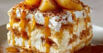 A glass dessert layered with caramelized apples, mascarpone cream and soaked ladyfingers, topped with salted butter caramel and cocoa powder.