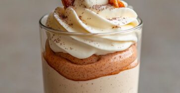 Mini glass verrines layered with creamy speculoos mousse and vanilla whipped cream, decorated with speculoos biscuit pieces and dusted with cocoa powder.