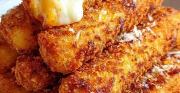 Golden homemade mozzarella sticks with a crispy breadcrumb coating, served hot with marinara sauce for dipping.