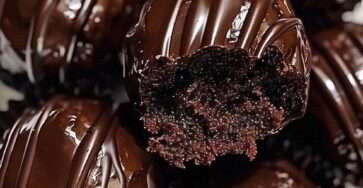 Chocolate coated Oreo truffles arranged on parchment paper with smooth glossy chocolate shell and cookie crumb decoration on top.