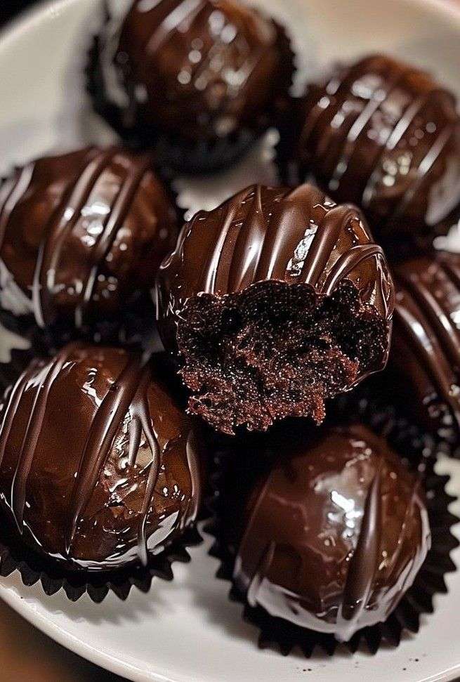 Chocolate coated Oreo truffles arranged on parchment paper with smooth glossy chocolate shell and cookie crumb decoration on top.
