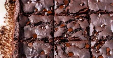 Fudgy black bean brownies cut into squares, made with cocoa powder and maple syrup, served on parchment paper in a baking dish.