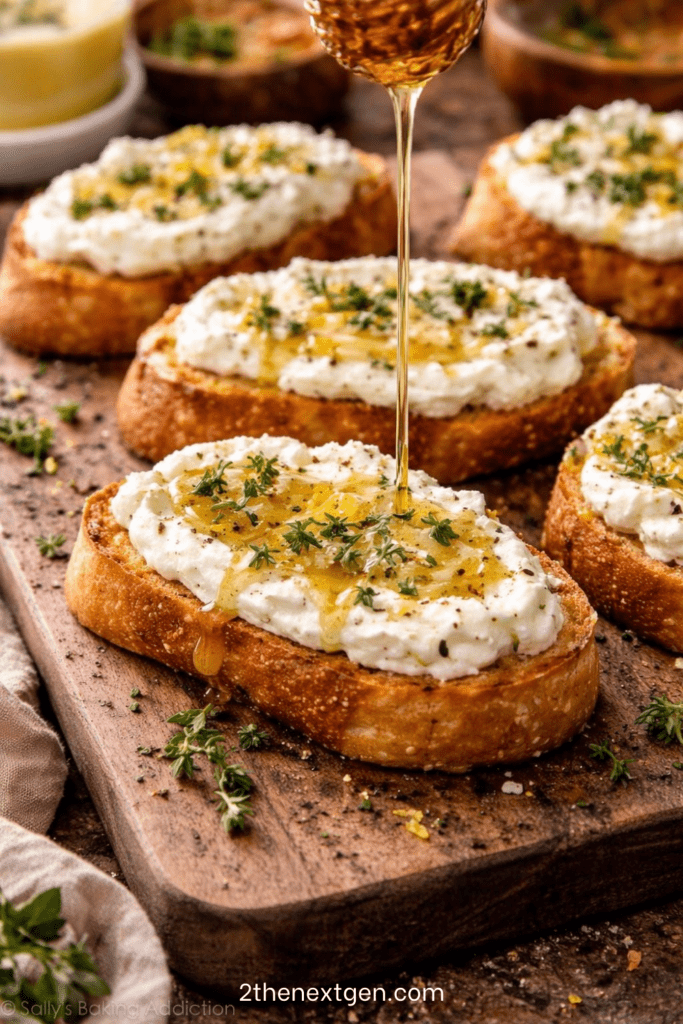 Golden toasted baguette slices topped with whipped feta cheese, drizzled with honey and garnished with fresh thyme leaves on a serving platter. feta and honey crostini