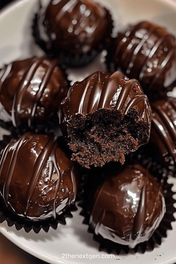 Chocolate coated Oreo truffles arranged on parchment paper with smooth glossy chocolate shell and cookie crumb decoration on top.