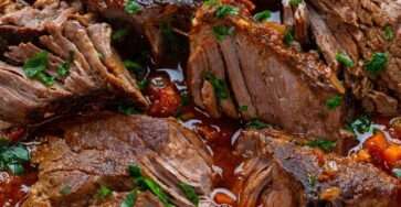 Italian stracotto pot roast braised in tomato and red wine sauce with carrots, celery and herbs served in a rustic Dutch oven.