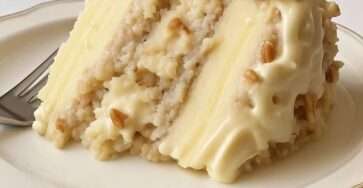 A chilled Snowy Bavarian Bliss Cake topped with creamy custard, shredded coconut and chopped pecans, served in a rectangular baking dish.