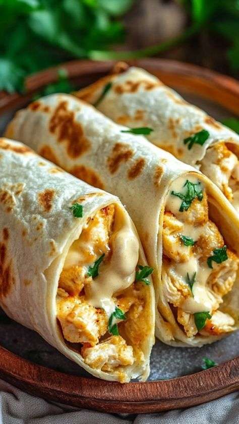 Cheesy garlic chicken wraps filled with seasoned chicken, melted cheddar and mozzarella cheese, grilled tortilla wrap cut in half on plate.