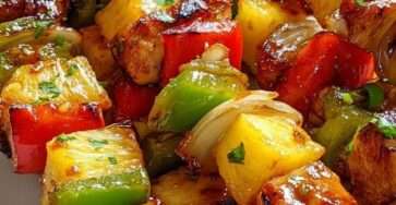 Grilled chicken skewers with pineapple chunks, bell peppers and red onion brushed with BBQ glaze on a hot grill.