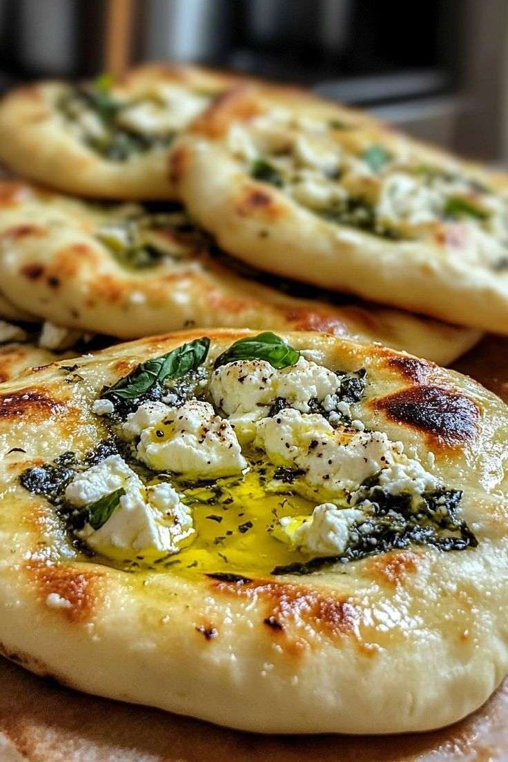 Mediterranean Golden pan-fried stuffed flatbread filled with feta, fresh mint, and spinach, brushed with olive oil and garnished with herbs.