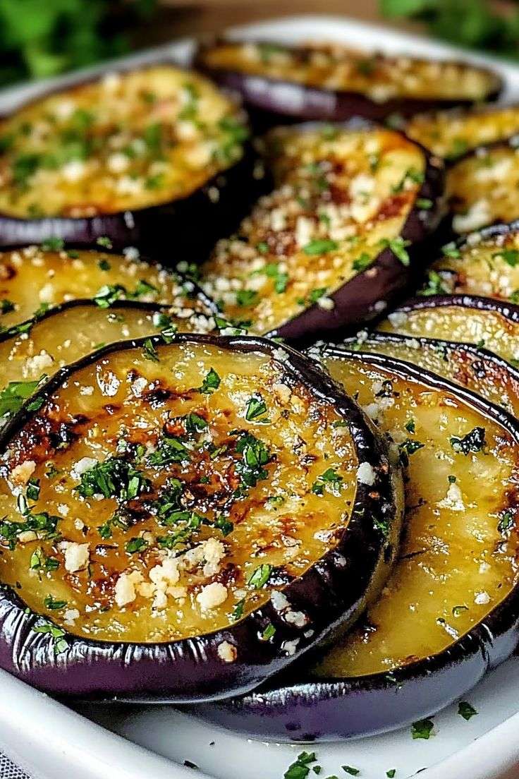 Mediterranean Golden roasted eggplant rounds brushed with lemon garlic olive oil, garnished with fresh parsley and served on a rustic platter.