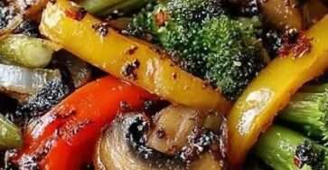 Colorful vegetable stir fry with broccoli florets, sliced mushrooms, red and yellow bell peppers coated in glossy soy sesame sauce in a wok.