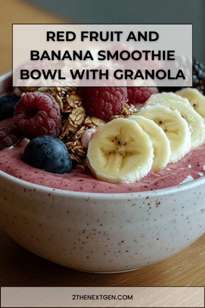Thick red fruit smoothie bowl topped with banana slices, raspberries, blueberries, and crunchy granola