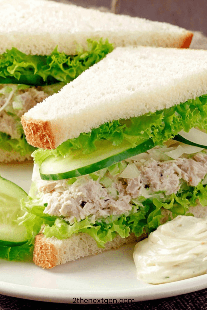 Mini tuna cucumber and lettuce appetizer sandwiches cut into triangles with creamy tuna filling and fresh cucumber slices