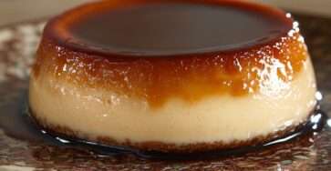 Ultra-creamy homemade caramel flan unmolded on a plate with glossy caramel sauce flowing around the smooth custard