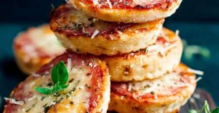 Easy mini crispy pizza bites topped with melted mozzarella, salami slices, tomato sauce, and fresh basil leaves