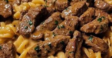 Creamy pasta tossed with seared steak strips in a garlic butter Parmesan cream sauce, finished with parsley and black pepper in a skillet
