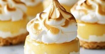 Mini lemon meringue cheesecakes with a buttery biscuit crust, creamy lemon filling, tangy lemon curd layer, and toasted golden meringue topping.