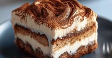 Classic Italian tiramisu dessert layered with coffee-soaked ladyfingers and creamy mascarpone filling, topped with a dusting of unsweetened cocoa powder.