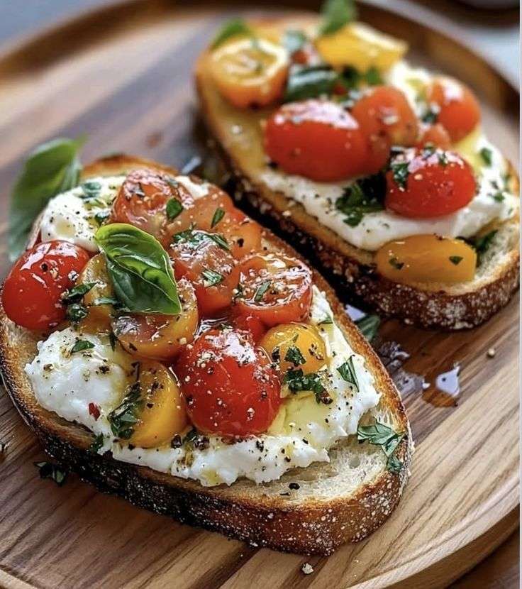 Toasted bread rounds topped with torn burrata bruschetta and marinated cherry tomatoes, basil, olive oil, and balsamic juices, served as an Italian appetizer