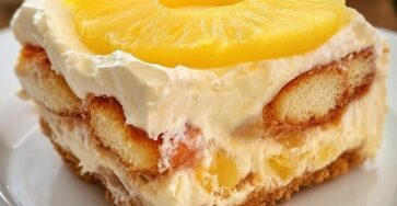 No-bake pineapple mascarpone dessert served in a glass dish with layers of juice-soaked cookies, smooth mascarpone cream, pineapple chunks, and a pineapple slice on top.