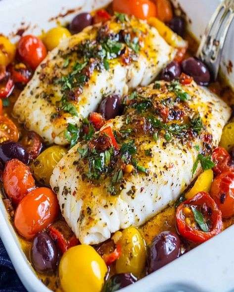 Mediterranean baked cod fillets with cherry tomatoes, olives, garlic, lemon, parsley, basil, and olive oil served in a baking dish.