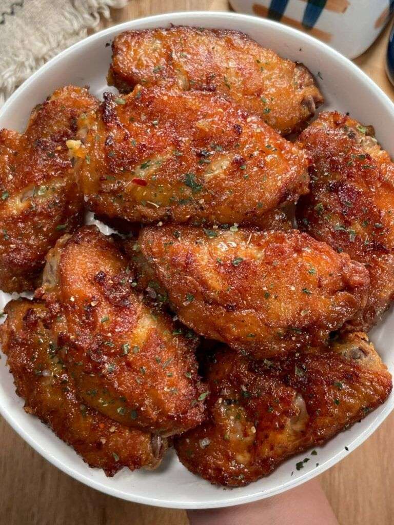 Crispy spicy chicken wings coated in sticky honey hot sauce glaze, sprinkled with parsley and chili flakes, served hot with dipping sauce.