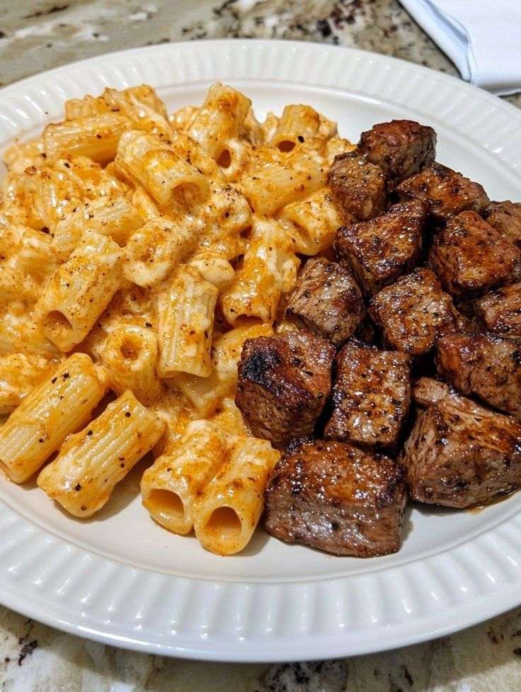 Creamy cheesy rigatoni pasta served with tender garlic butter steak bites, parmesan, parsley, and a rich homemade cheese sauce.