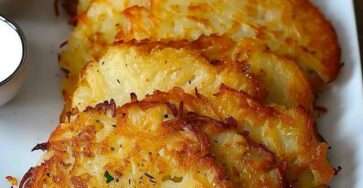 Golden crispy potato pancakes served warm with sour cream, fresh parsley, and sweet chili sauce on a rustic plate.