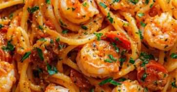 Creamy tomato shrimp spaghetti served with tender shrimp, cherry tomatoes, parmesan, black pepper, and fresh parsley on top.