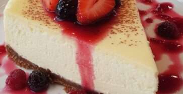 Classic cheesecake topped with homemade berry sauce, fresh strawberries, blueberries, raspberries, mint leaves, and a buttery biscuit crust.