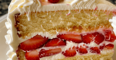 Strawberry cream layer cake with soft vanilla cake layers, mascarpone whipped cream filling, sliced fresh strawberries, and whole strawberries on top.