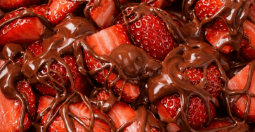 Chocolate covered strawberries bowl with fresh sliced strawberries drizzled with melted chocolate, topped with chopped nuts, coconut, biscuit crumbs, and white chocolate drizzle.