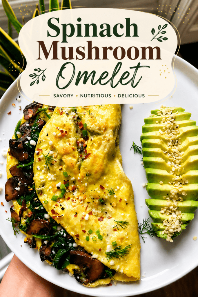 Mushroom spinach omelette served with sliced avocado, crumbled feta cheese, fresh herbs, sesame seeds, black pepper, and a small squeeze of lemon.