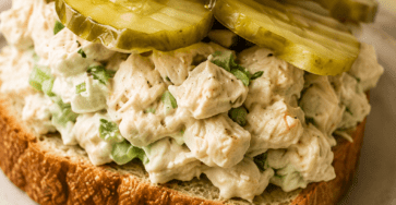Close-up of pickle chicken salad sandwiches filled with creamy shredded chicken, crunchy dill pickles, fresh herbs, lettuce, and soft sandwich bread.