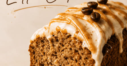 Close-up of banana bread latte cake slice with moist banana crumb, cinnamon coffee glaze, caramel drizzle, chopped walnuts, and a warm coffee cup in the background.