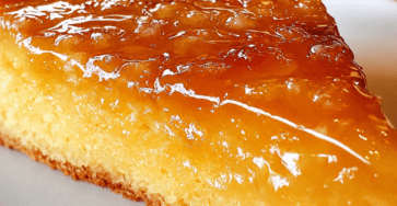 A moist orange marmalade semolina cake sliced on a plate with a glossy citrus topping, golden crumb, orange zest, and a soft syrup-soaked texture.