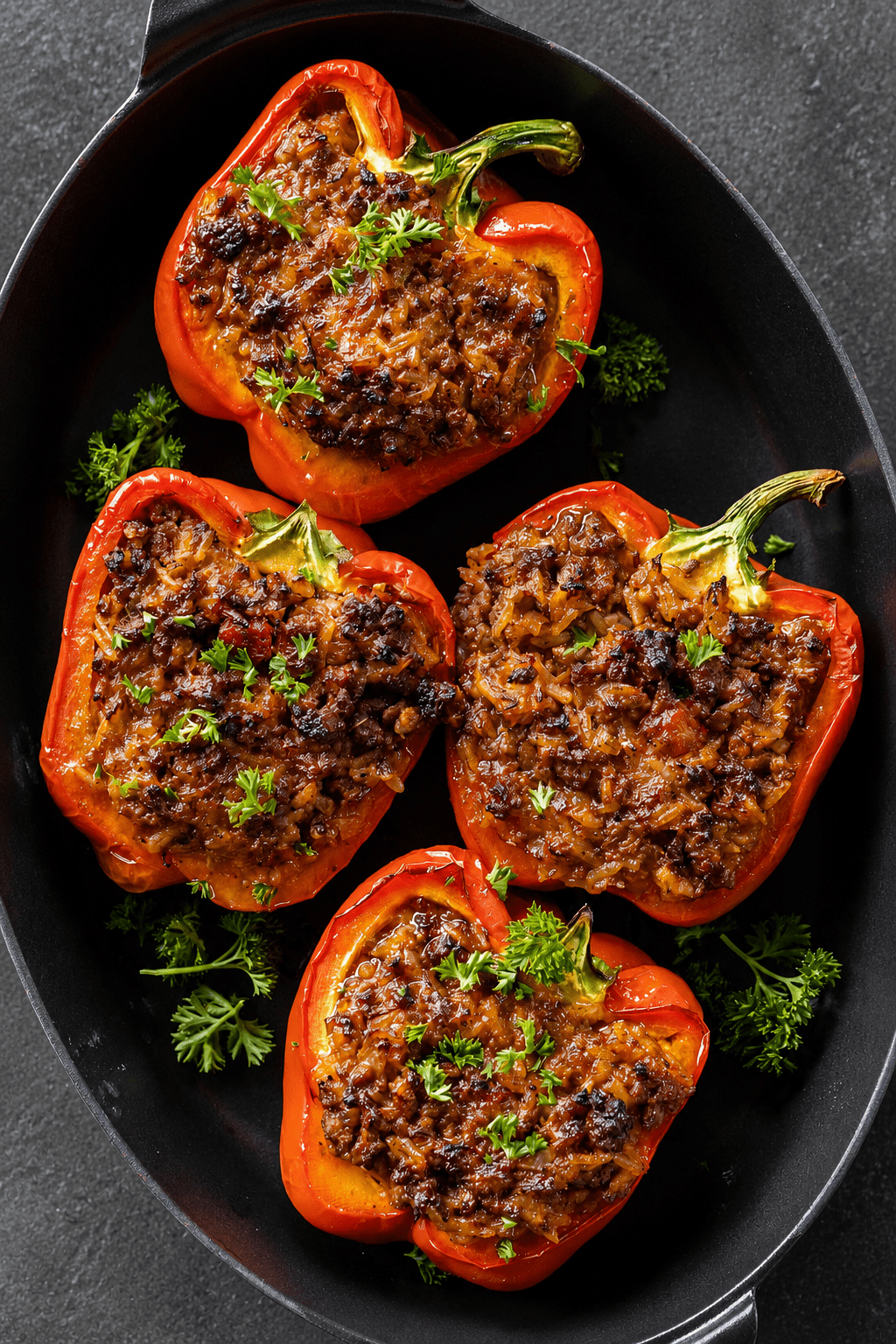 Baked stuffed red bell peppers filled with seasoned ground beef, rice, tomato sauce, herbs, and melted cheese, served hot with fresh parsley on top.