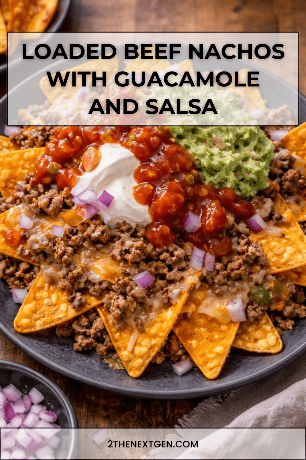Loaded beef nachos served on a tray with crispy tortilla chips, seasoned ground beef, melted cheddar, guacamole, salsa, sour cream, red onion, jalapeños, and fresh cilantro.