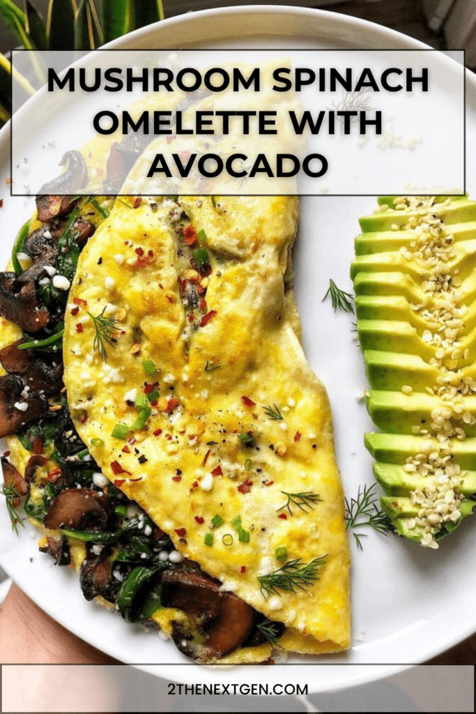Mushroom spinach omelette served with sliced avocado, crumbled feta cheese, fresh herbs, sesame seeds, black pepper, and a small squeeze of lemon.