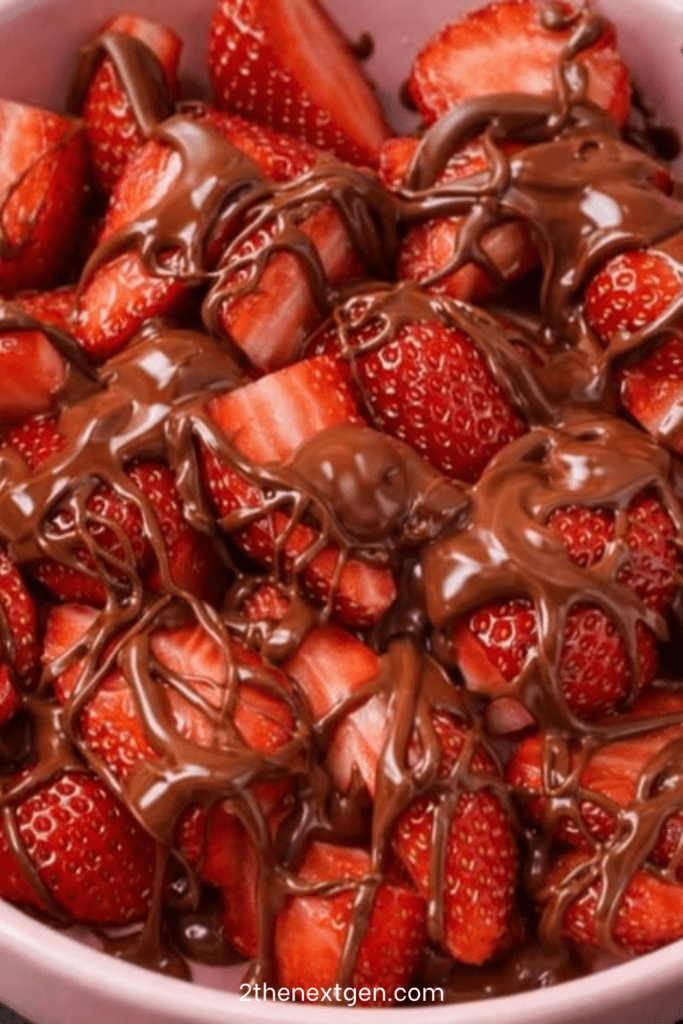 A white ceramic bowl filled with fresh red strawberry halves heavily drizzled with shiny melted dark chocolate against a clean white background.
