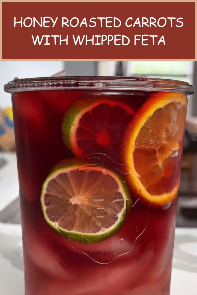 Refreshing berry citrus iced drink served with orange, lemon, lime slices, fresh berries, mint leaves, ice cubes, and sparkling water.