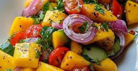 Fresh mango cucumber salad with ripe mango cubes, cucumber, cherry tomatoes, red onion, cilantro, lime dressing, and chili flakes.