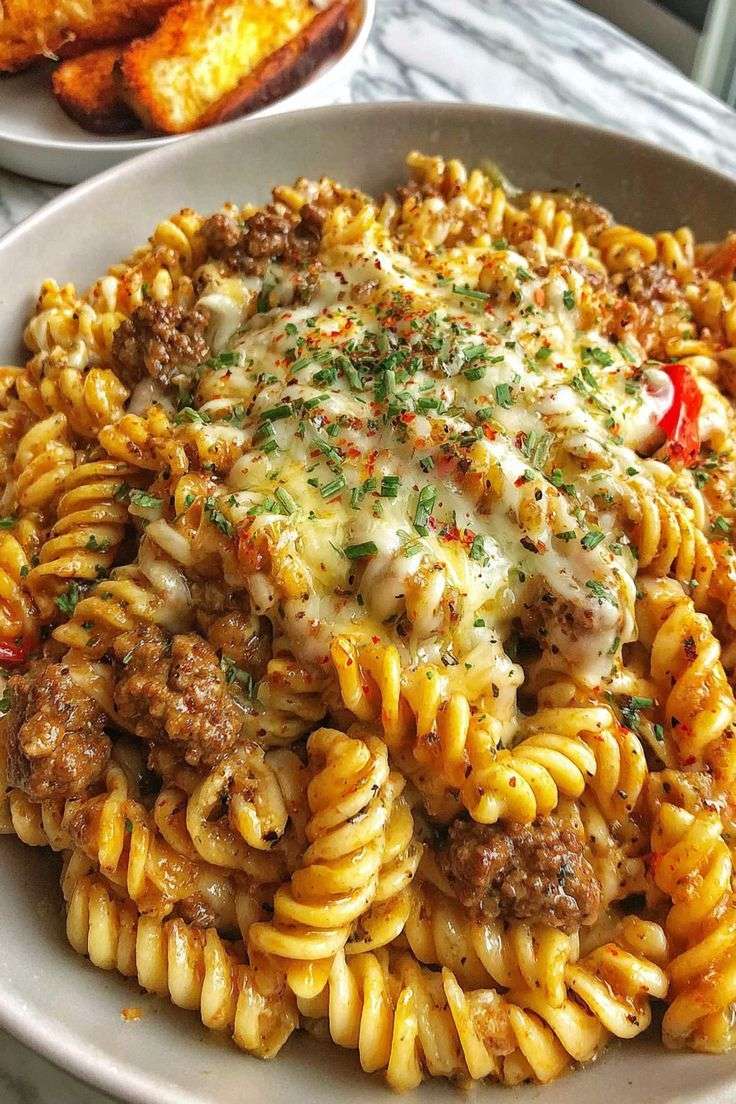 Cheesy beef fusilli pasta bake served hot with melted mozzarella, cheddar, parmesan, rich beef tomato sauce, and fresh parsley.